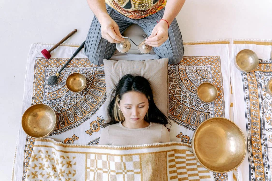 A woman meditating cross-legged on a wooden floor at home